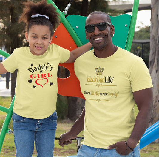 Man and young girl wearing matching yellow t-shirts at a playground.