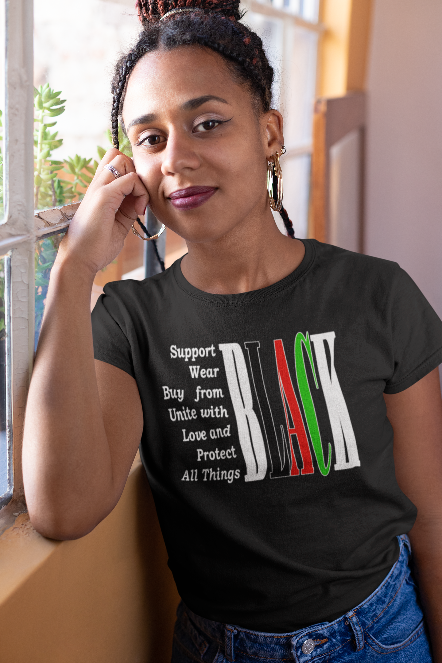 Woman wearing a black t-shirt with a message and rainbow design, standing indoors.