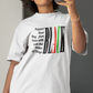 Person taking a mirror selfie wearing a white t-shirt with a graphic design in a bedroom.