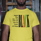 Man wearing a yellow t-shirt with text and colors, standing against a graffiti-covered wall.