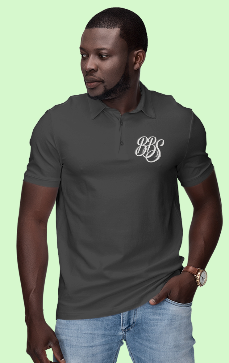 Man wearing a dark gray polo shirt with a logo on a light green background