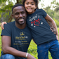 Man and child in matching outfits outdoors on a grassy area