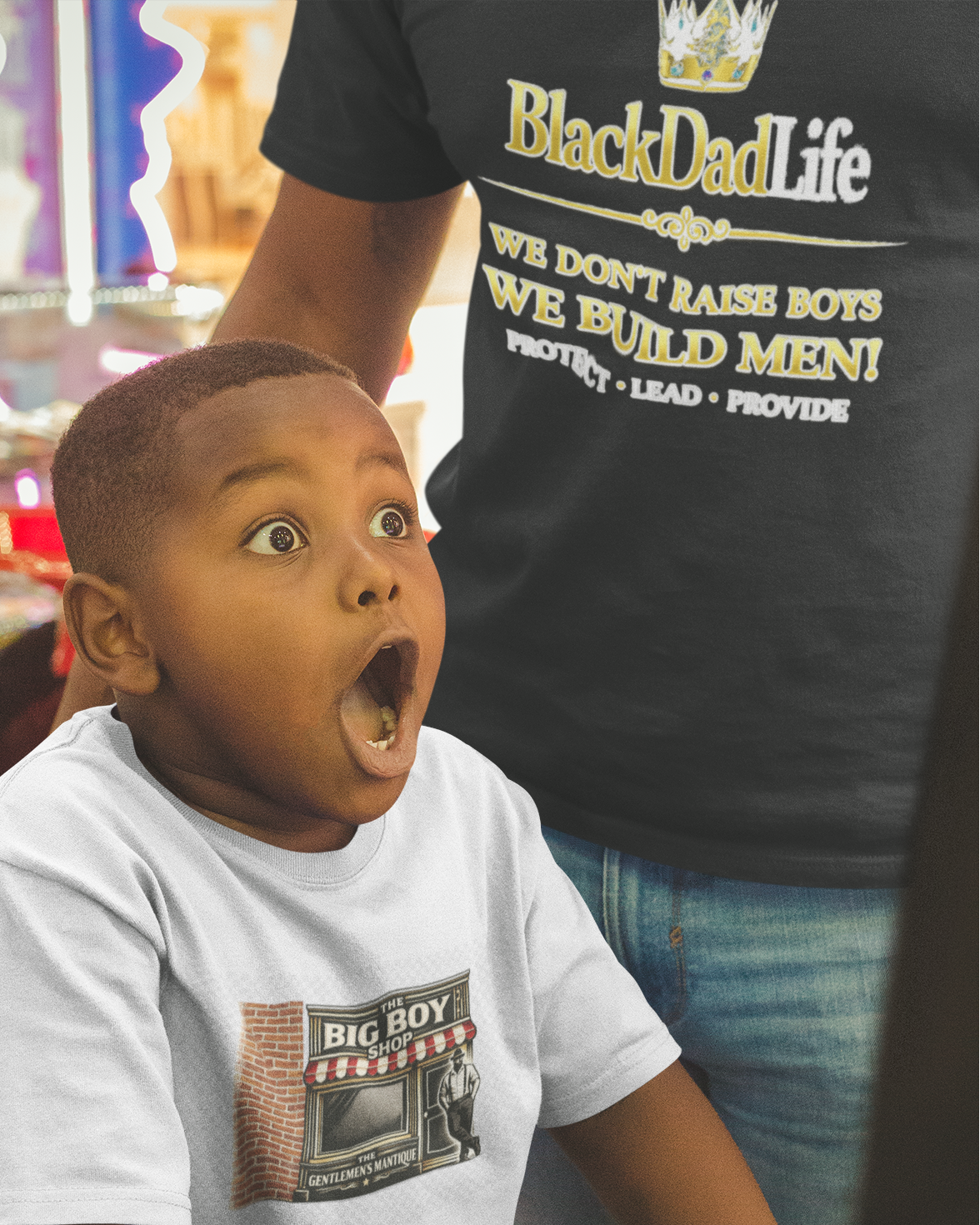 Child in a toy store with a surprised expression, wearing a 'Black Dad Life' t-shirt.