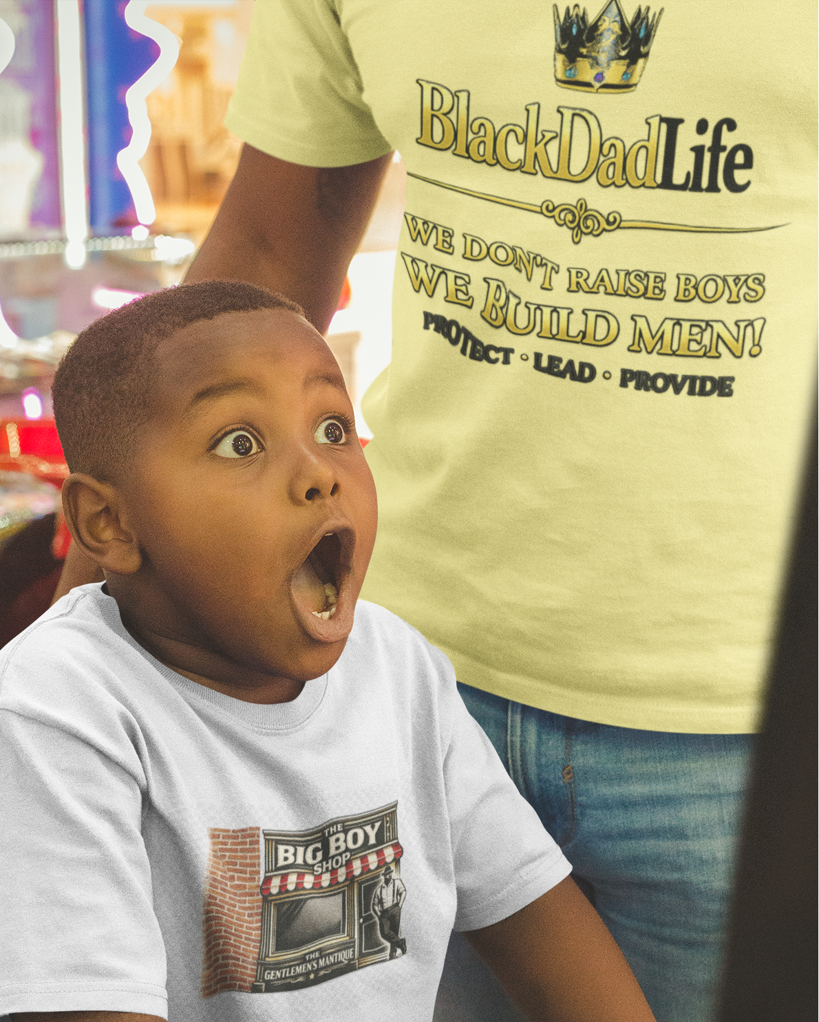Child in a toy store with a surprised expression, wearing a 'Big Boy' t-shirt.
