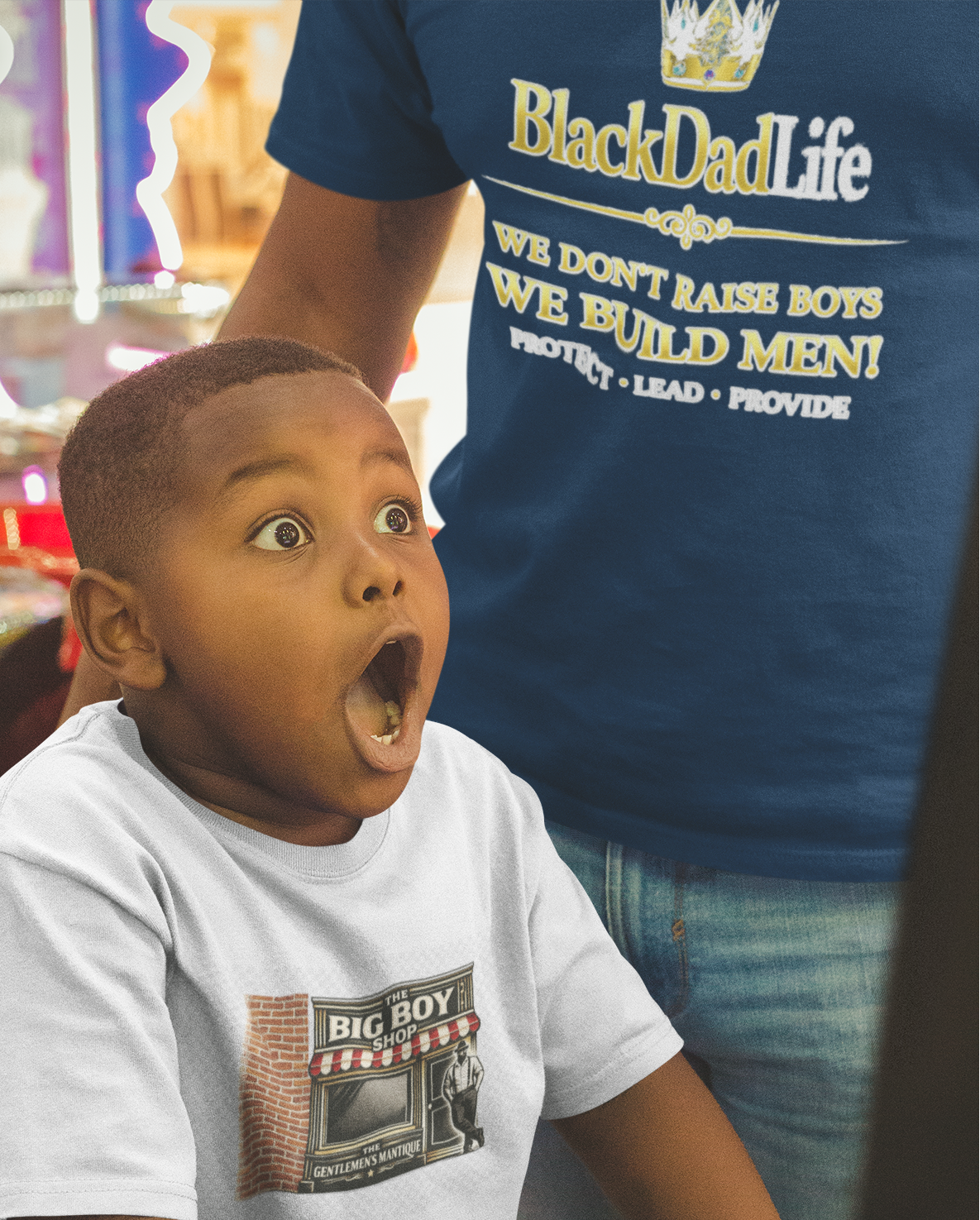 Child in a toy store with a surprised expression, wearing a 'Black Dad Life' t-shirt.