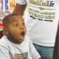 Child in a toy store wearing a 'Big Boy' t-shirt with an adult in a 'Black Dad Life' t-shirt in the background.