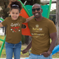 Man and young girl wearing matching 'Daddy's Little Queen' and 'BackDadLife' t-shirts outdoors.