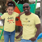 Man and young girl wearing matching yellow t-shirts at a playground.