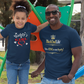 Man and young girl wearing matching blue t-shirts standing on a playground.