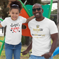 Man and young girl standing together on a playground, both wearing white t-shirts.