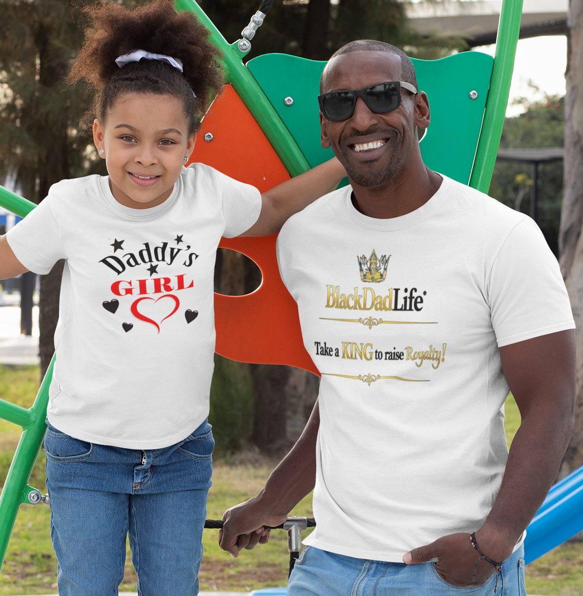 Man and young girl standing together on a playground, both wearing white t-shirts.