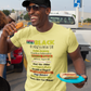 Man wearing a yellow t-shirt with 'Black History Month' text, holding a hot dog, standing outdoors.