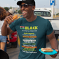 Man wearing a colorful t-shirt with text, holding a hot dog, and standing in an outdoor setting.