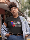 Person wearing a black t-shirt with text and graphics, standing on a street.