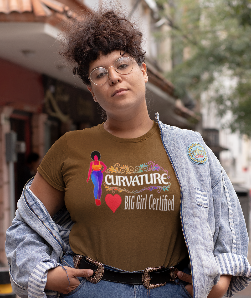 Person wearing a brown t-shirt with text and graphics, standing on a street.