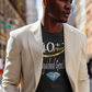 Man wearing a beige blazer over a black graphic t-shirt on a city street.