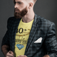 Man wearing a yellow t-shirt with text and graphics, paired with a plaid blazer on a dark background