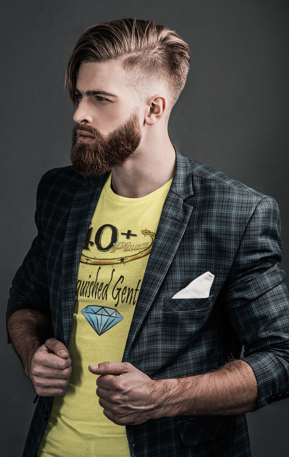 Man wearing a yellow t-shirt with text and graphics, paired with a plaid blazer on a dark background