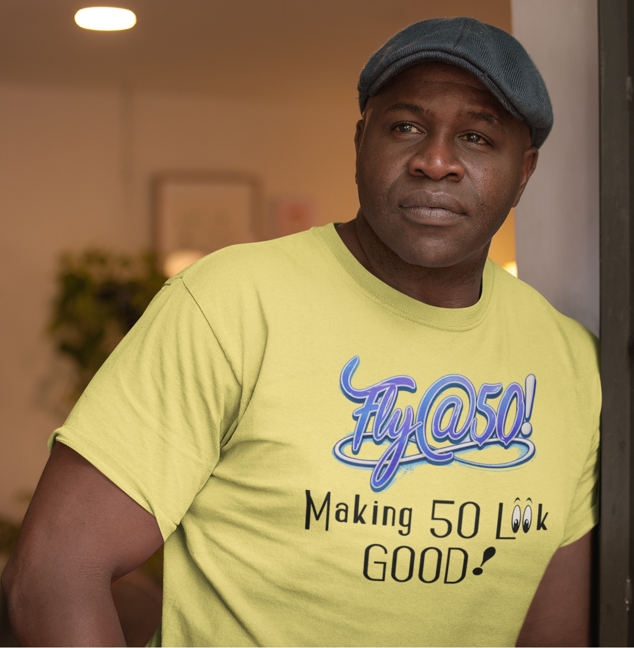 Man wearing a yellow t-shirt with text, standing indoors.