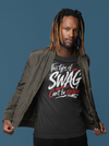 Man wearing a black t-shirt with text, dark pants, and a gray jacket on a blue background