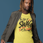 Man wearing a yellow t-shirt with text, black pants, and white shoes on a blue background