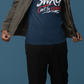 Man wearing a blue t-shirt with text, black pants, and white shoes on a blue background
