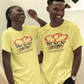 Two people wearing yellow t-shirts with a heart design, standing outdoors.