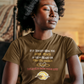 Woman meditating in a cozy room wearing a brown t-shirt with text.