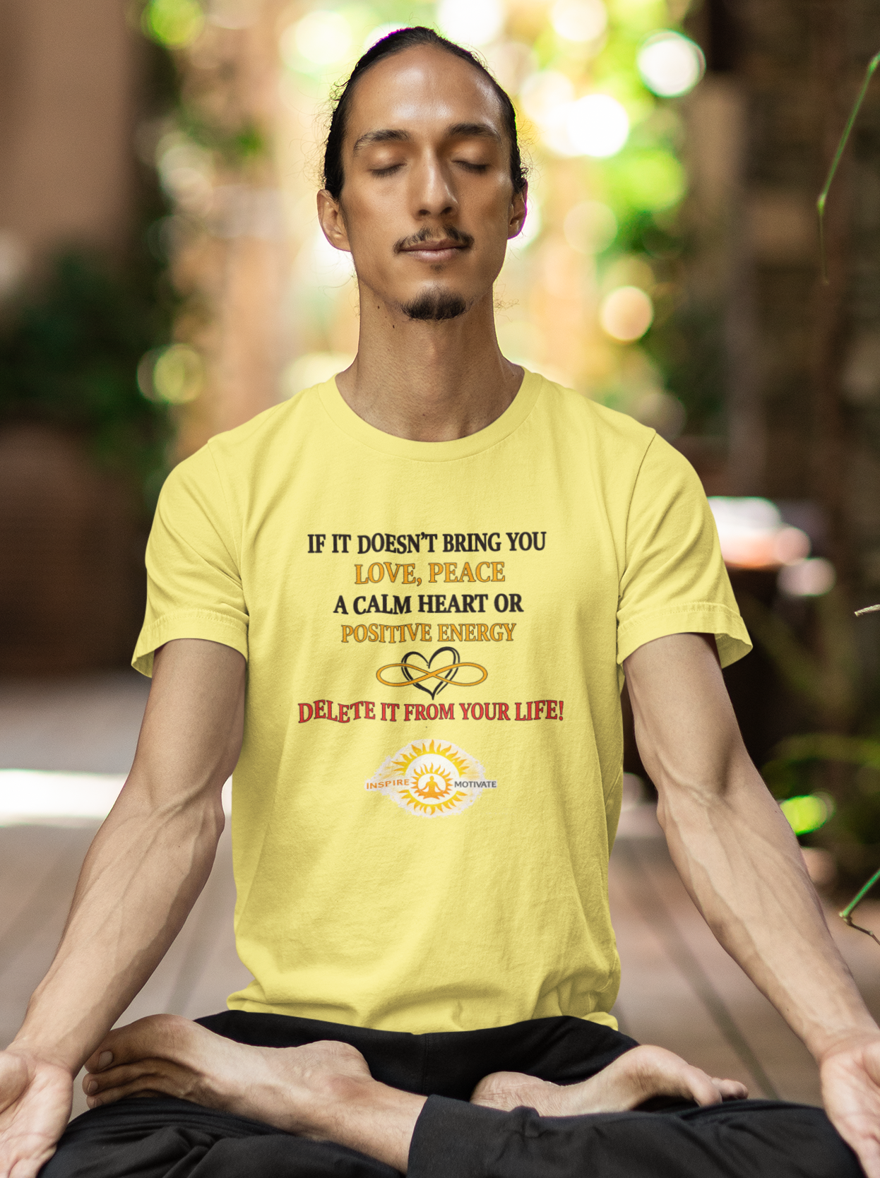 Man in a yellow shirt meditating outdoors on a wooden deck.