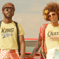 Two people standing in front of a vintage car with a suitcase, wearing matching t-shirts with 'KING' and 'QUEEN'.