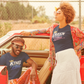 Two people standing next to a red car, wearing matching 'King' and 'Queen' shirts.