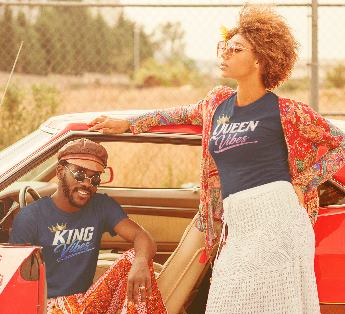 Two people standing next to a red car, wearing matching 'King' and 'Queen' shirts.